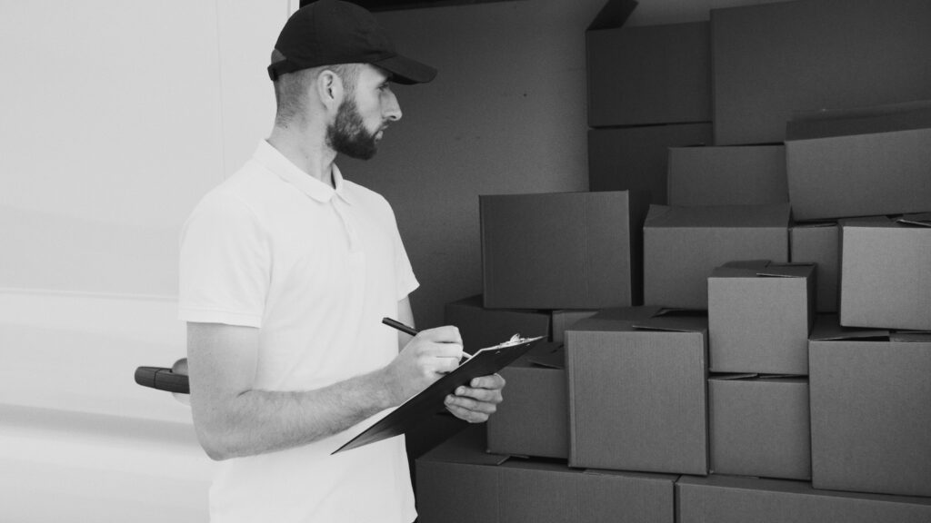 A delivery man inspecting cardboard boxes in a van, preparing for shipment.